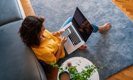 kvinde i sofa med computer og mobil
